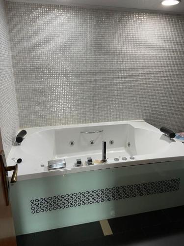 a white bath tub in a bathroom with a tile wall at Appartement mobilart haut standing in Oran