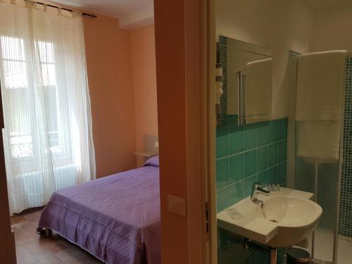 a bathroom with a sink and a bed and a mirror at Perla Nera Guesthouse in Imperia