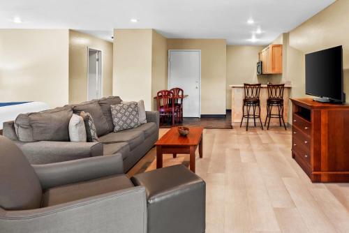 a living room with a couch and a tv and a kitchen at Baymont by Wyndham Yakima Riverfront in Yakima