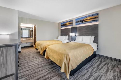 a hotel room with two beds and a television at Quality Inn Glasgow in Glasgow