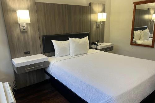 a bedroom with a large white bed with a mirror at The Dylan, a Baymont by Wyndham in Seattle