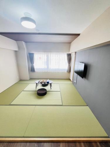 a room with a green floor with a table and a window at 福の荘 美野島 in Fukuoka