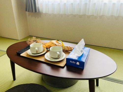 a coffee table with two cups and a box on it at 福の荘 美野島 in Fukuoka