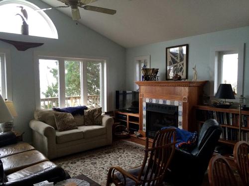 un salon avec un canapé et une cheminée dans l'établissement Bayfront Cottage Rental with a Private Beach on Virginia's Eastern Shore, à Onancock
