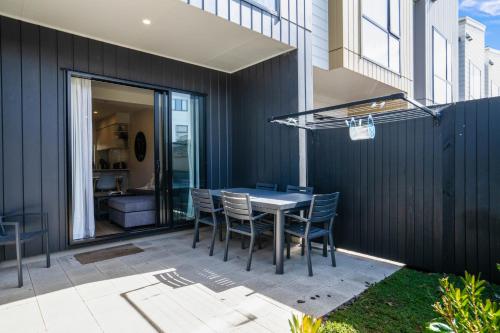 a dining area with a table and chairs on a patio at Huntington Townhouse with Patio and Parking in Auckland