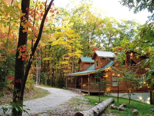 a log cabin in the woods next to a road at Spectacular Cabin Rental for Large Groups near New River in West Virginia in Hico