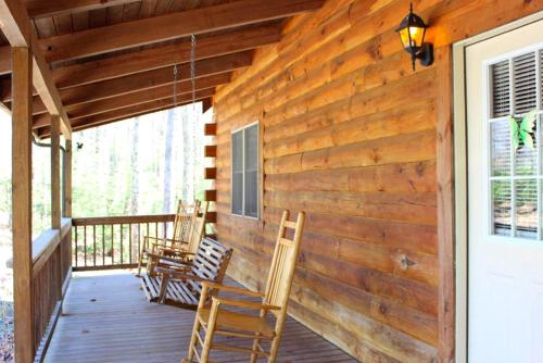 a wooden porch with rocking chairs on it at Spectacular Cabin Rental for Large Groups near New River in West Virginia in Hico