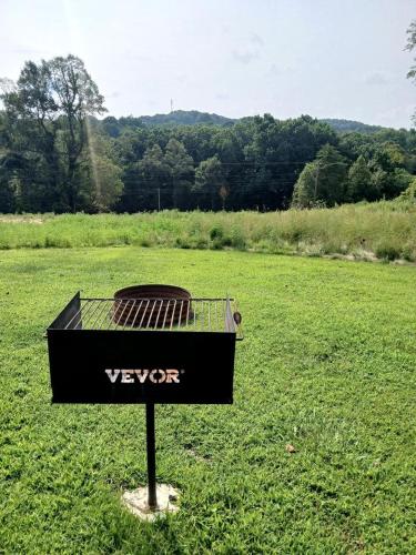 a grill in the middle of a grass field at Fantastic Secluded Tented Cabin with Fire Pit in Logan, Ohio in Logan