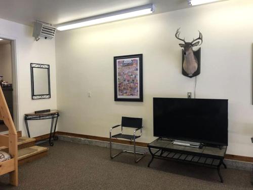 a living room with a flat screen tv and a deer head on the wall at Mountain View Cabin with Deck, Jacuzzi and Ping Pong Table in Montana in West Glacier