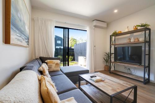 a living room with a couch and a tv at Huntington Townhouse with Patio and Parking in Auckland