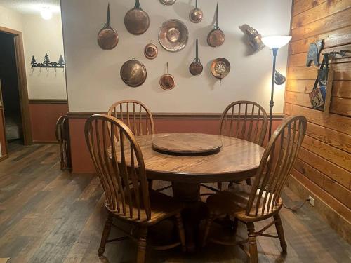a wooden table with four chairs and bowls on the wall at Rustic Log Cabin Rental near Chattahoochee National Forest, Georgia in Hiawassee