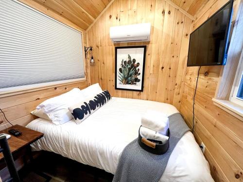 a bedroom with a bed with a television and a chair at Rustic Tiny House Glamping in Grand Junction: Authentic Rural Charm in Colorado in Grand Junction