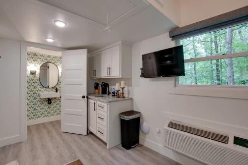 a kitchen with white cabinets and a sink and a window at Sweet Tiny House Nestled Among the Towering Trees in Alabama in Grant