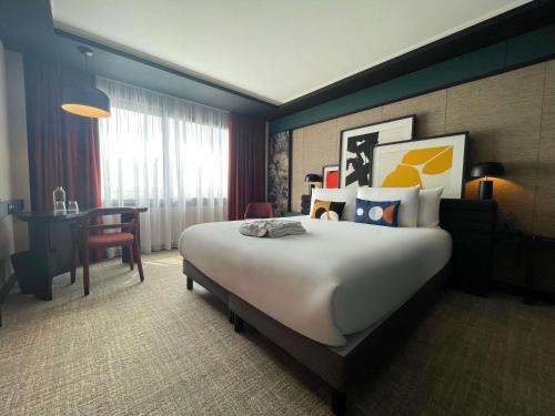 a hotel room with a large bed and a desk at Mercure Dijon Centre Clemenceau in Dijon