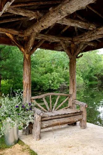 a wooden bench sitting under a gazebo with flowers at Secluded Cottage Rental with a Heated Pool in Red Hook for Family Getaways in New York State in Mount Ross