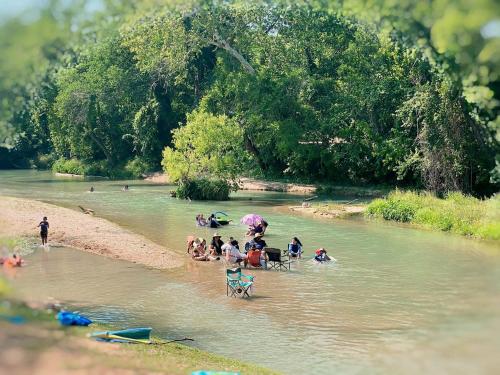 a group of people sitting on chairs in a river at Dream Glamping Destination Suitable for Families: Comfortable Safari Tent on the San Marcos River near Kingsbury, Texas in Staples