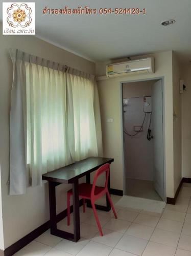 a room with a table and a red chair next to a window at Huern Che Ta One Hotel in Phrae