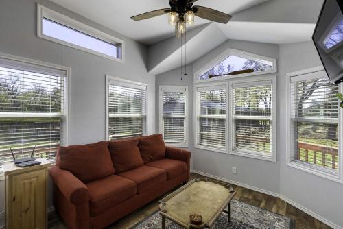 a living room with a brown couch and windows at Intimate Chic Cabin Suitable for Four with Private Deck in Texas in Emory