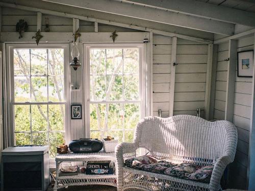 a room with two windows and a chair and a table at Off-The-Grid Cottage Rental with Beautiful Views on Crow Island, Maine in Georgetown
