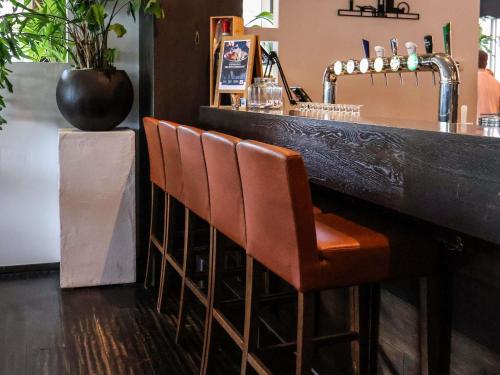 a bar with orange chairs and a counter with a sink at Mercure Hotel Tilburg Centrum in Tilburg