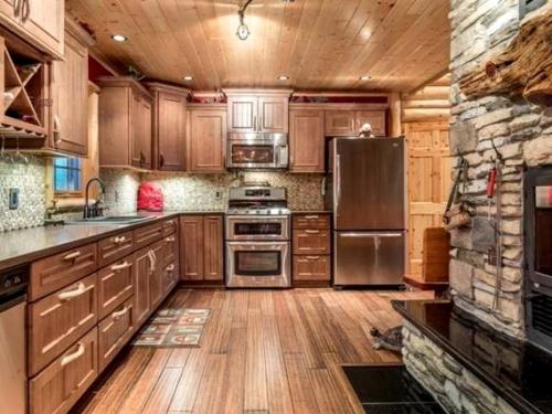 a kitchen with wooden cabinets and stainless steel appliances at Log Cabin Elegance: Your Private Haven on 5 Acres of Hazelhurst Waterfront in Hazelhurst