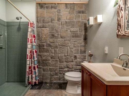 a bathroom with a toilet and a stone wall at Log Cabin Elegance: Your Private Haven on 5 Acres of Hazelhurst Waterfront in Hazelhurst