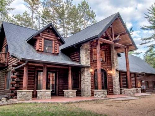 a log cabin with a black roof at Log Cabin Elegance: Your Private Haven on 5 Acres of Hazelhurst Waterfront in Hazelhurst