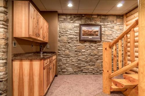 a kitchen with wooden cabinets and a stone wall at Log Cabin Elegance: Your Private Haven on 5 Acres of Hazelhurst Waterfront in Hazelhurst