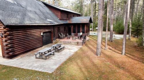 a log cabin with a picnic table and benches at Log Cabin Elegance: Your Private Haven on 5 Acres of Hazelhurst Waterfront in Hazelhurst