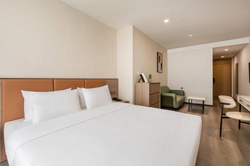 a bedroom with a large white bed and a living room at Chengying Hotel - Sanlitun Taikoo Li in Beijing