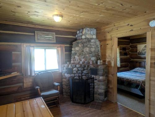 a room with a stone fireplace in a log cabin at Tranquil Weekend Getaway Close to Chequamegon National Forest in Wisconsin in New Post
