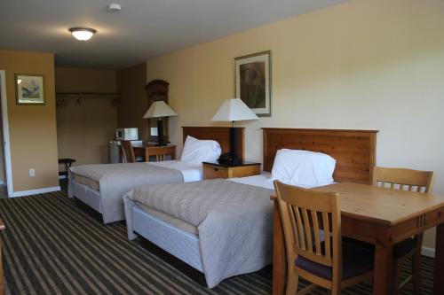Cette chambre comprend 2 lits et une table. dans l'établissement Berkshire Travel Lodge, à Canaan