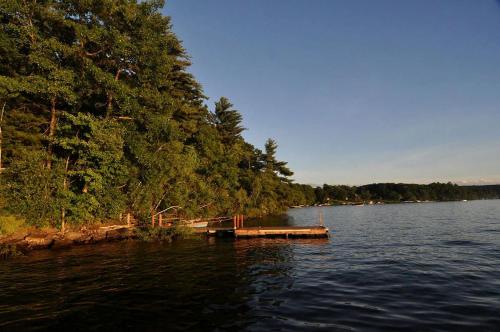 a dock in the middle of a lake with trees at Lakefront Cabin Rental with Incredible Sunsets on Lake Wallenpaupack, Pennsylvania in Tafton