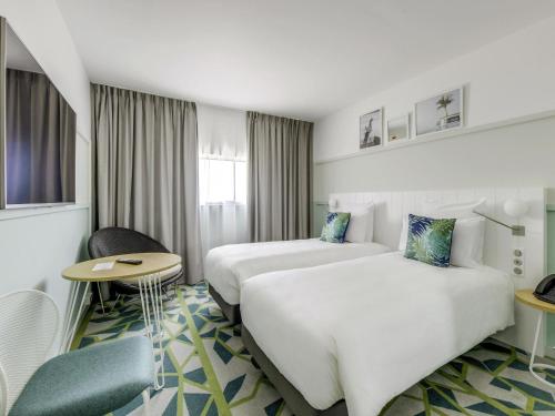 a hotel room with two beds and a table at Mercure Paris Orly Airport in Orly