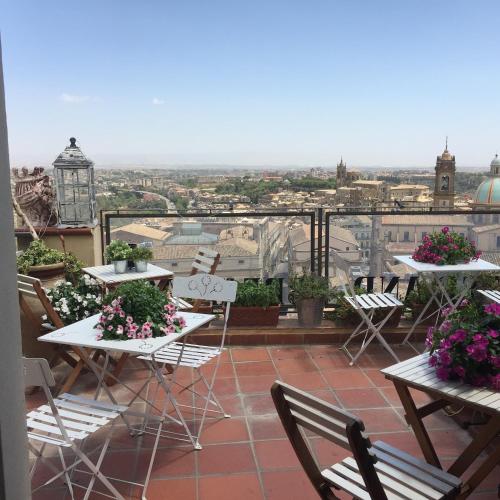 a balcony with tables and chairs with flowers on it at Casa tipica siciliana patronale home BedandBreakfast TreMetriSoprailCielo Camere con vista, colazione interna in terrazzo panoramico in Caltagirone