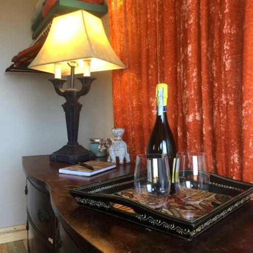 a bottle of wine on a table with a lamp and glasses at Romantic Yucca Valley Cabin with Hot Tub in Yucca Valley
