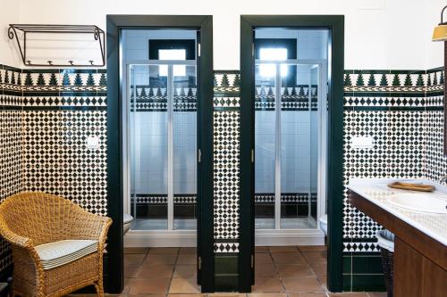 a bathroom with two glass shower stalls and a chair at Hacienda Los Manchones in Aguilar de la Frontera