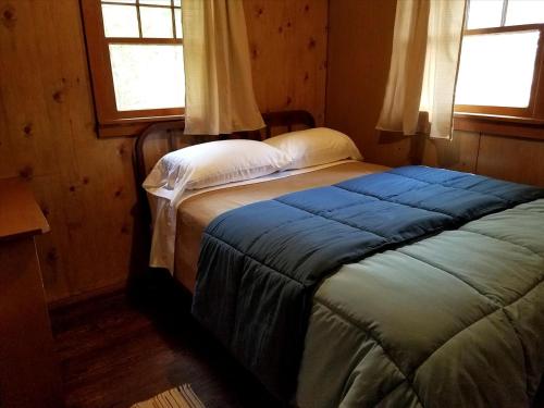 - un lit dans une chambre avec 2 fenêtres dans l'établissement Gorgeous Getaway Cabin in the Woods near Lake Michigan in Wellston, Michigan, à Wellston