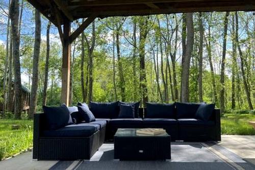 a blue couch sitting on a patio with trees at Tranquil Riverside Getaway in Western NY for 3 in Belfast in Oramel
