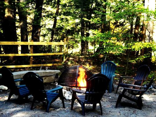 a group of chairs around a table with a fire at Rustic Woodland Cabin Rental near Oneida Lake, New York in Taberg