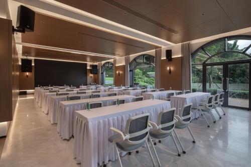 a conference room with white tables and chairs and a screen at Trip.com Group Country Retreats(Guangzhou Bella vita manor) in Huadong