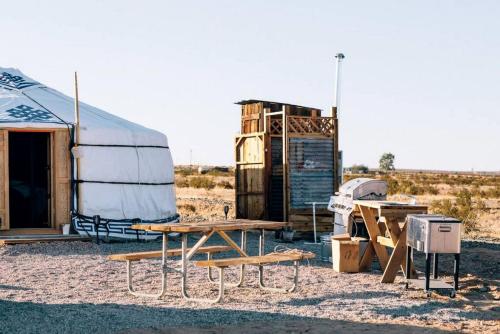a table and benches in front of a tent at Picturesque Yurt Fantastic for Stargazing near Joshua Tree National Park, California in Sunfair Heights