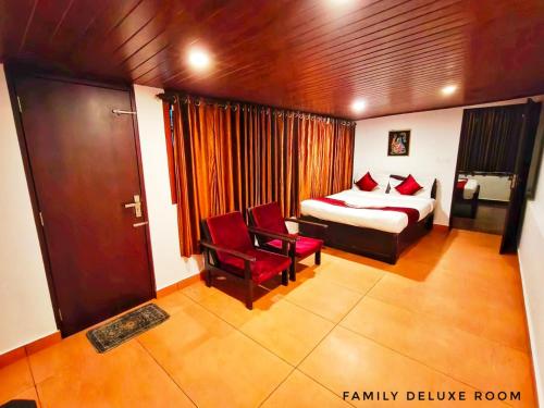 a bedroom with a bed and two red chairs at Casa Linda in Devikolam