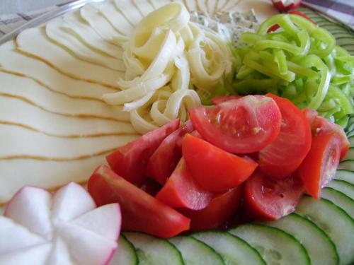 a plate of food with cucumbers tomatoes and other vegetables at Penzión Biela Voda in Veľká Lomnica