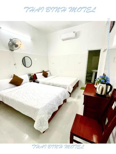 a bedroom with two beds and a desk with a table at Thai Binh Motel in Danang