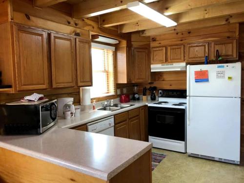 a kitchen with wooden cabinets and a white refrigerator at Rustic Cabin Rental near the Gauley River in West Virginia in Hico