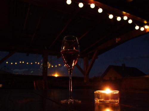 a glass of wine sitting on a table with a candle at Penzión Biela Voda in Veľká Lomnica