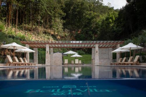 a swimming pool with chairs and umbrellas at Trip.com Group Country Retreats(Guangzhou Bella vita manor) in Huadong