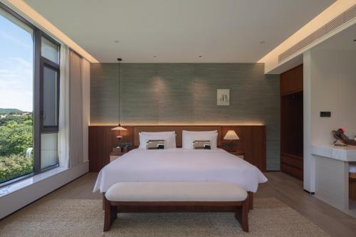 a bedroom with a white bed and a large window at Trip.com Group Country Retreats(Guangzhou Bella vita manor) in Huadong