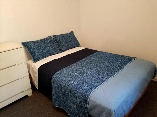 - une chambre avec un lit doté d'une couverture bleue et d'une commode dans l'établissement Charming Vacation Cabin with Waterfront Views on Pine Lake, Michigan, à Wellston